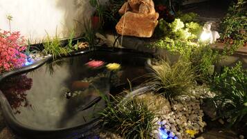Surrounded by lush plants and a decorative turtle, this serene garden pond creates a peaceful atmosphere.