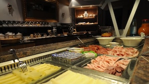 Un bufé con diversos alimentos, incluyendo carnes, quesos y frutas.