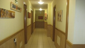 A hotel hallway with wooden wainscoting, tiled flooring, and artwork on the walls. - Pensión Residencia Caola (Arteixo)