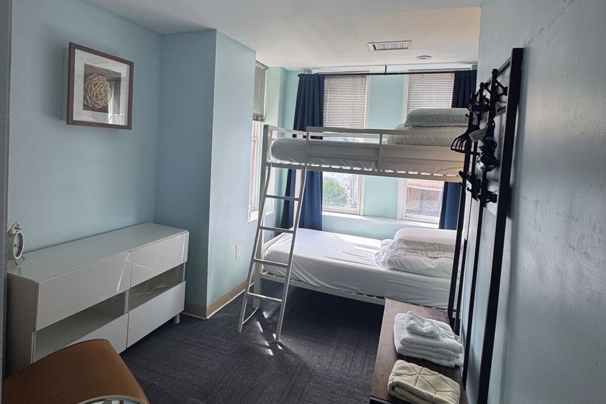 A compact hotel room with bunk beds, a desk, and a chair.