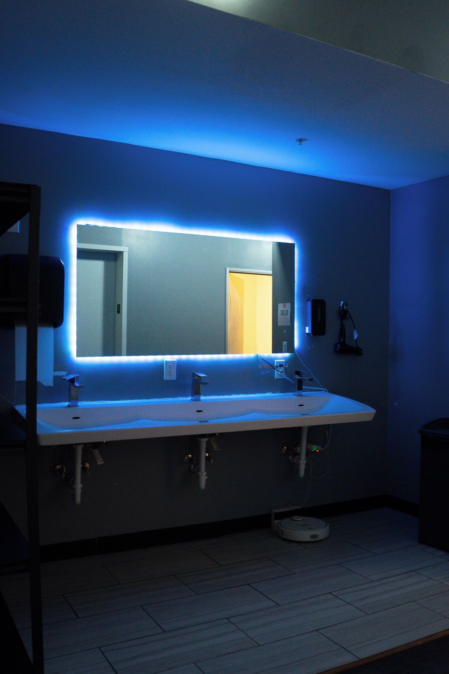 A bathroom with a double sink, a large mirror with LED lighting, and a toilet.