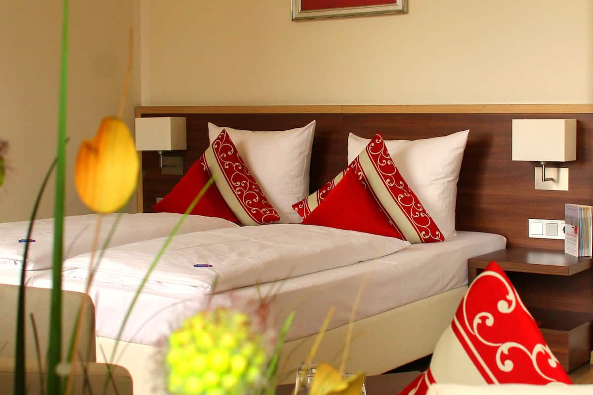 Quarto de hotel com uma cama, duas mesas de cabeceira e um criado-mudo.