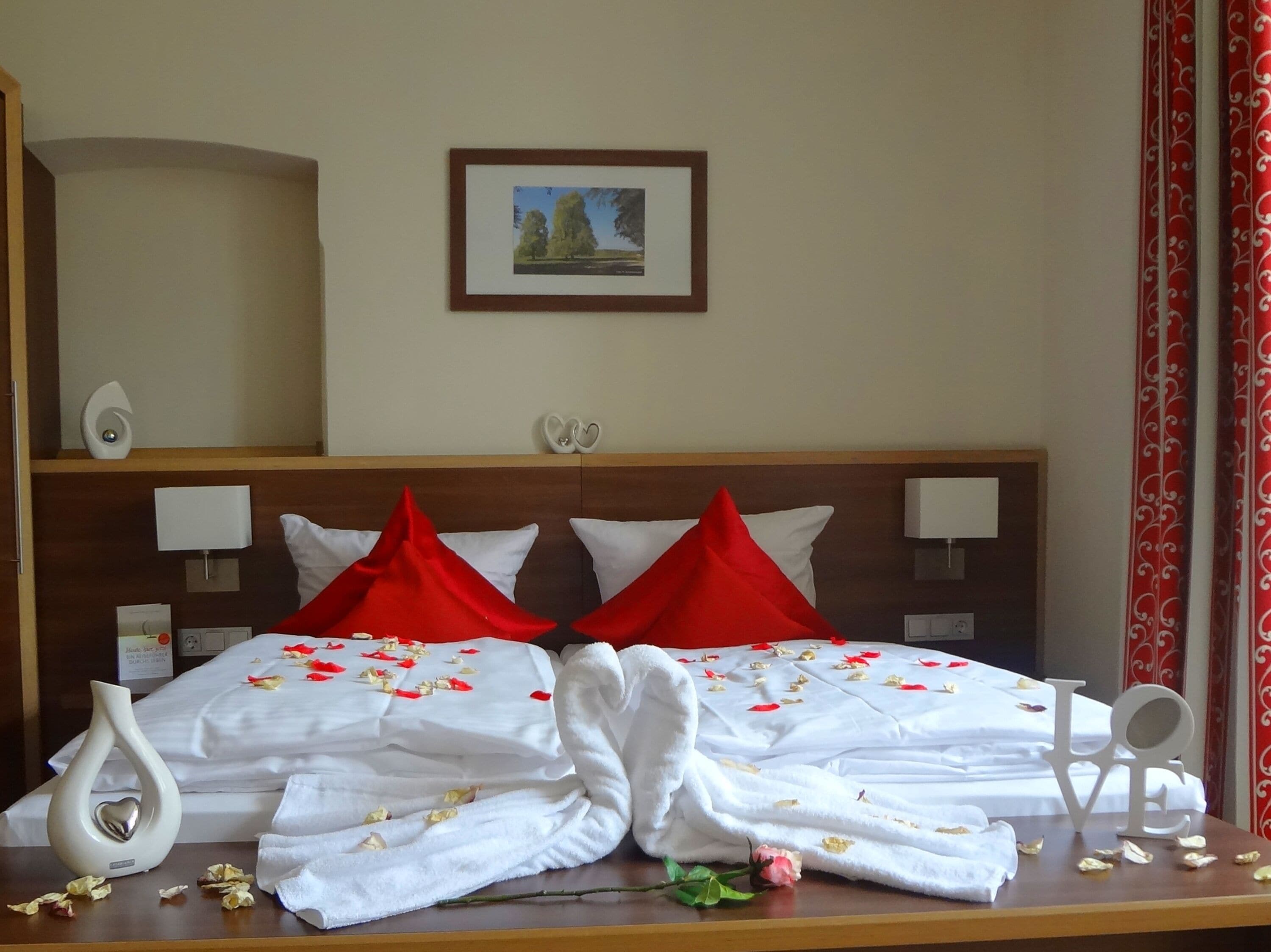 Una habitación de hotel con una cama bien hecha, un cuadro en la pared y un jarrón decorativo en la mesita de noche.
