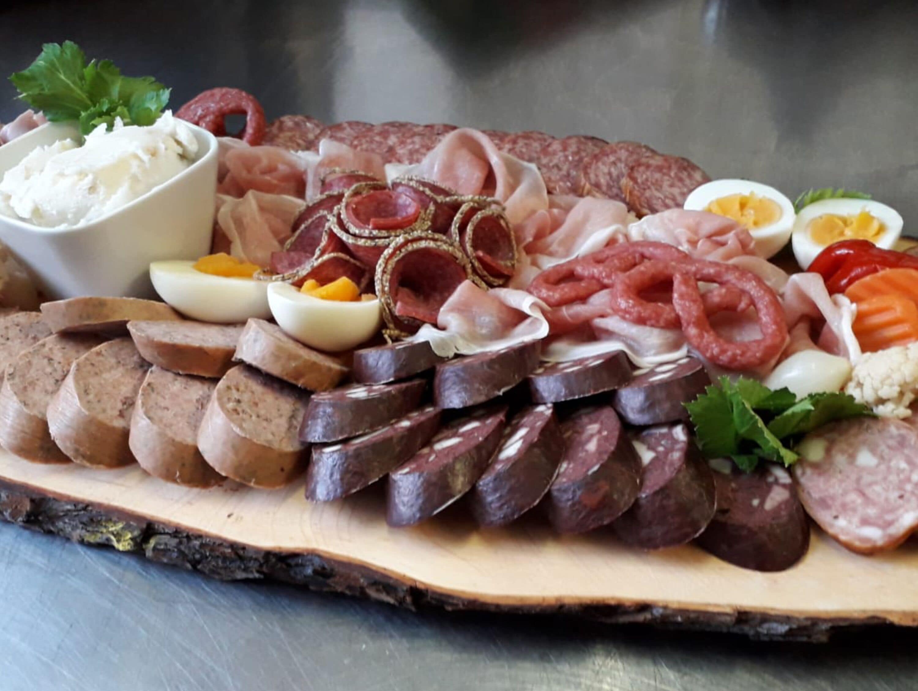 Une planche de charcuterie avec différentes sortes de viandes, d’œufs et de fromages.
