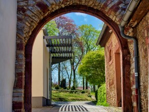 An arched entrance with a pergola and a pathway leading to a building.