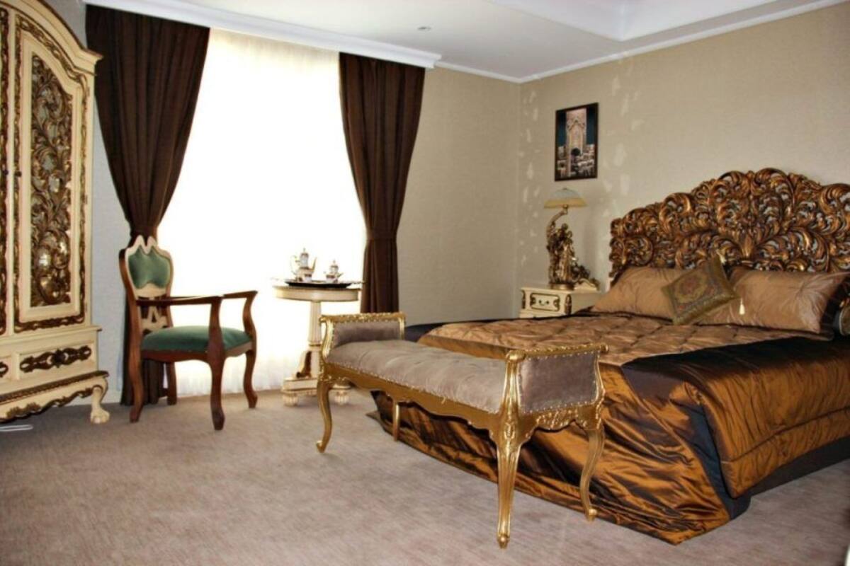 A bedroom with a large bed, a wooden chair, a dresser, and a nightstand.