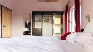Een hotelkamer met een groot bed, een televisie, een kledingkast en een spiegel.