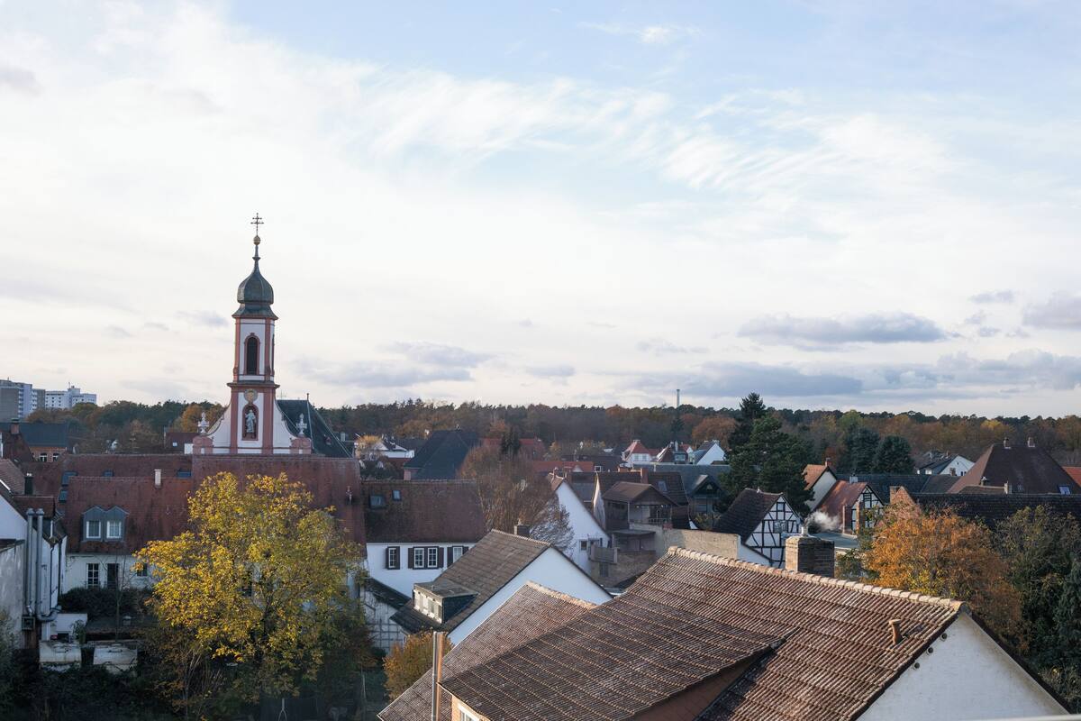 Eine Stadt mit einem markanten Kirchengebäude, das einen hohen Glockenturm und ein traditionelles Haus mit einem steilen Dach zeigt.