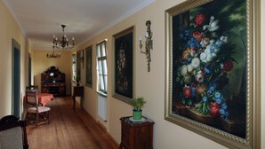 Een hal met houten vloeren, een eethoek met een tafel en stoelen, en een groot bloemschilderij aan de muur.
