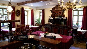 Een traditionele eetruimte met houten meubels, een bar met flessen en een kroonluchter.