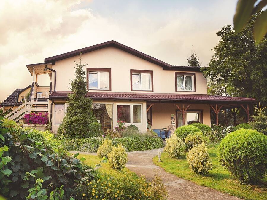 A two-story house with a covered porch, a front garden, and a staircase leading to the entrance.