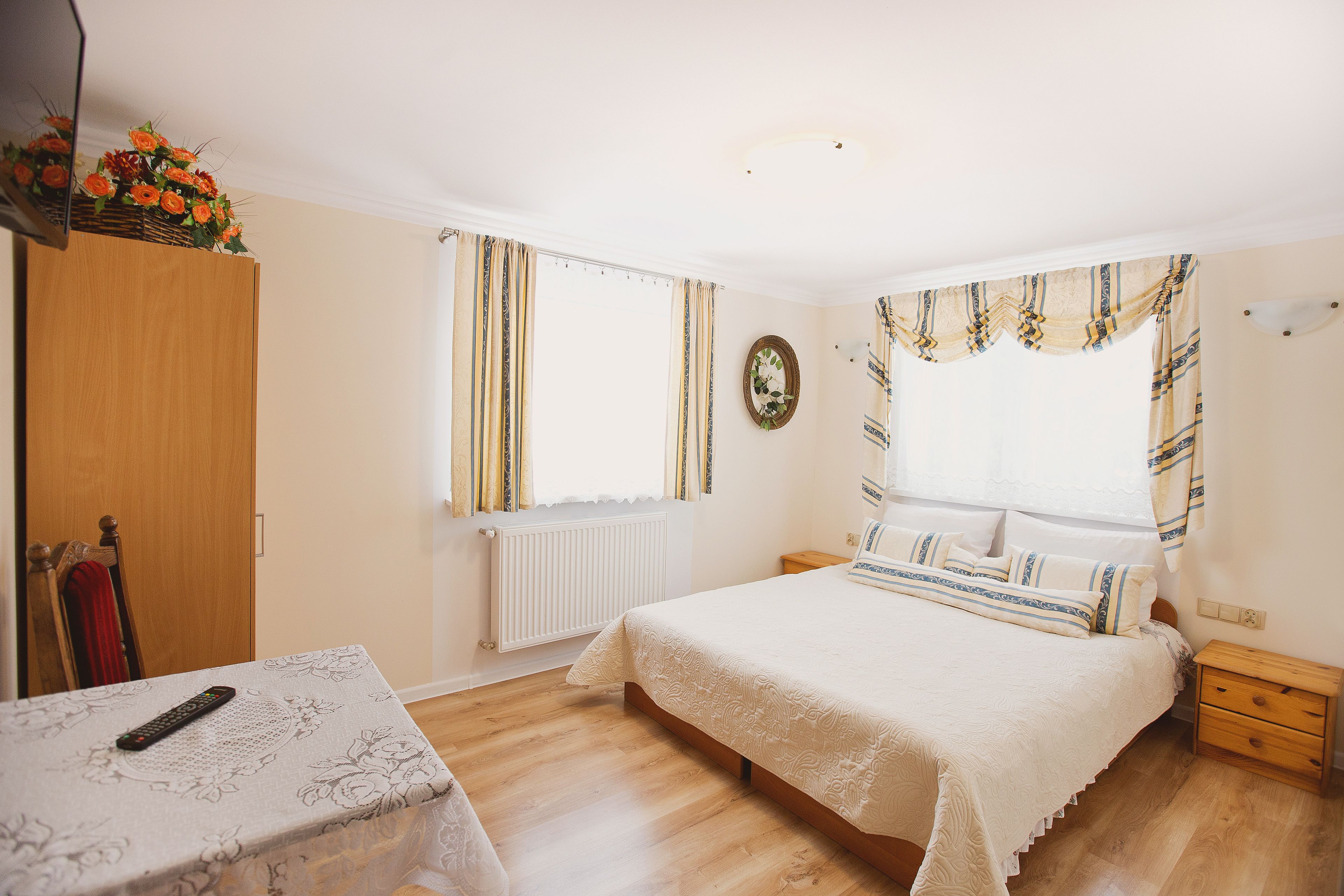 A bedroom with a bed, bedside table, and a window with curtains.