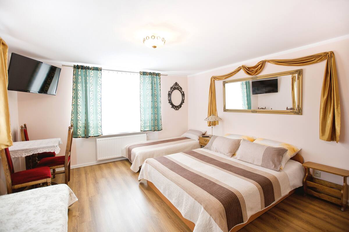 Une chambre d’hôtel avec deux lits, une télévision, un bureau et une chaise.