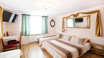 Una habitación de hotel con dos camas, televisión, escritorio y una silla.