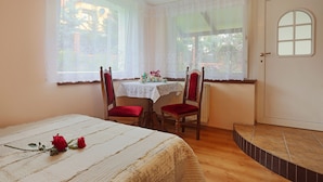 Een slaapkamer met een bed, een tafel met stoelen en een deur.