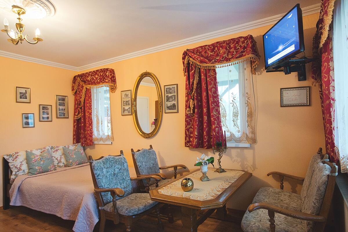 Un salon confortable avec un canapé, deux fauteuils, une table basse et un téléviseur.