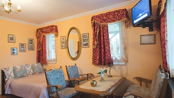 Ein gemütliches Wohnzimmer mit einer Couch, zwei Sesseln, einem Couchtisch und einem Fernseher.
