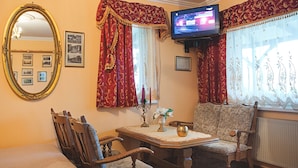 Een gezellige kamer met een televisie, een tafel met een vaas en twee stoelen.