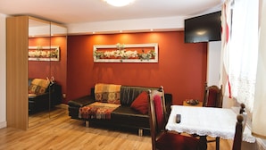 Een woonkamer met een bank, een tafel, een televisie en een spiegel.