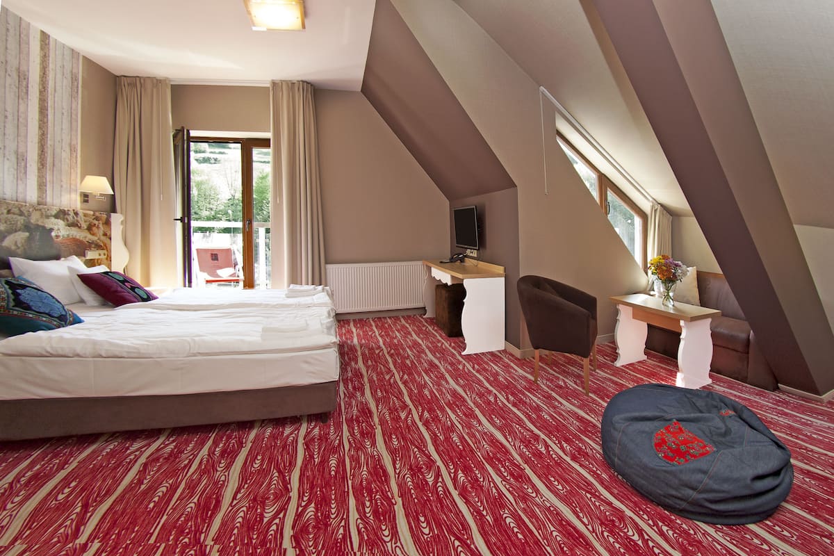 A hotel room with a bed, desk, chair, and a bean bag.