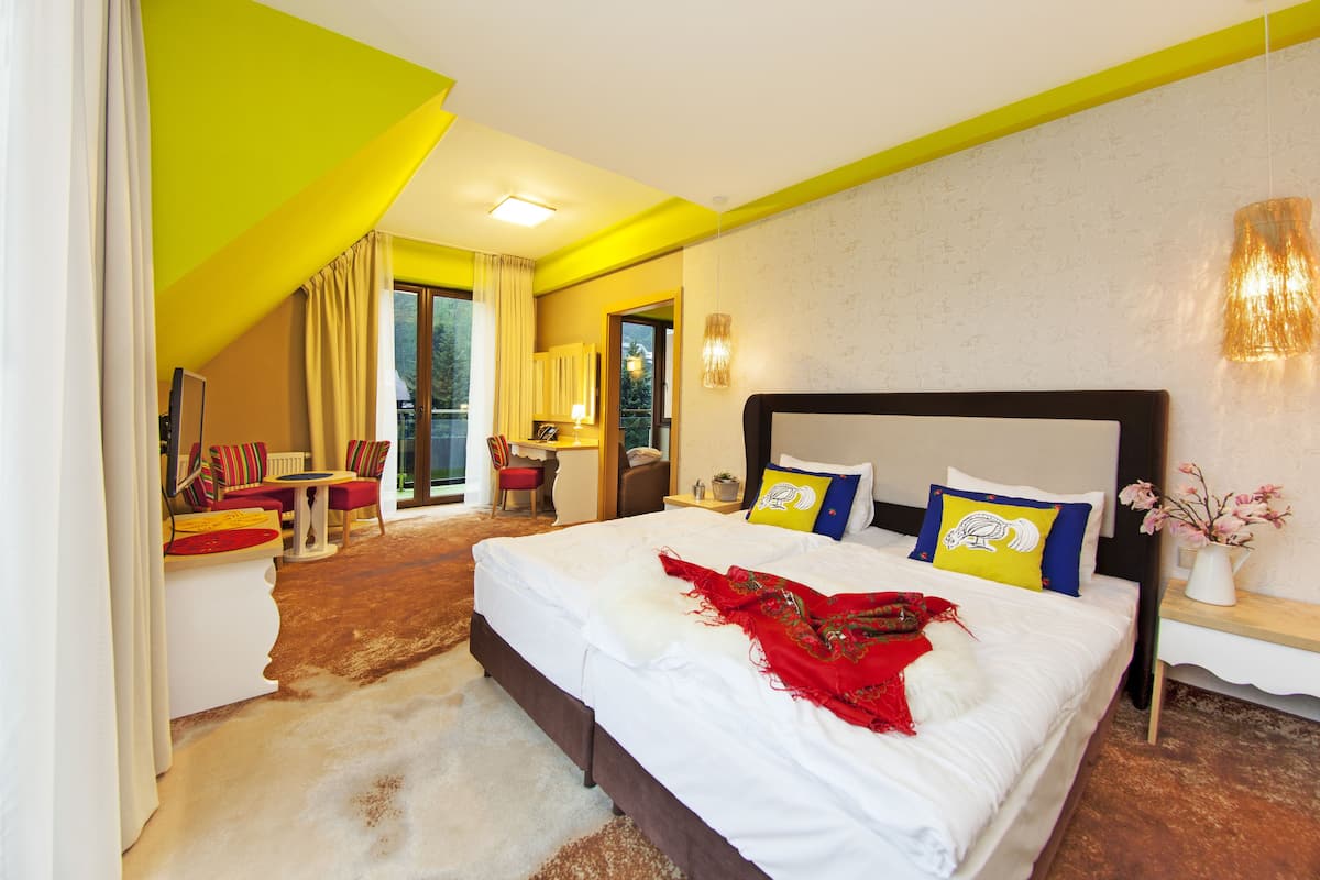 A hotel room with a large bed, a desk, a chair, and a view of the outdoors.