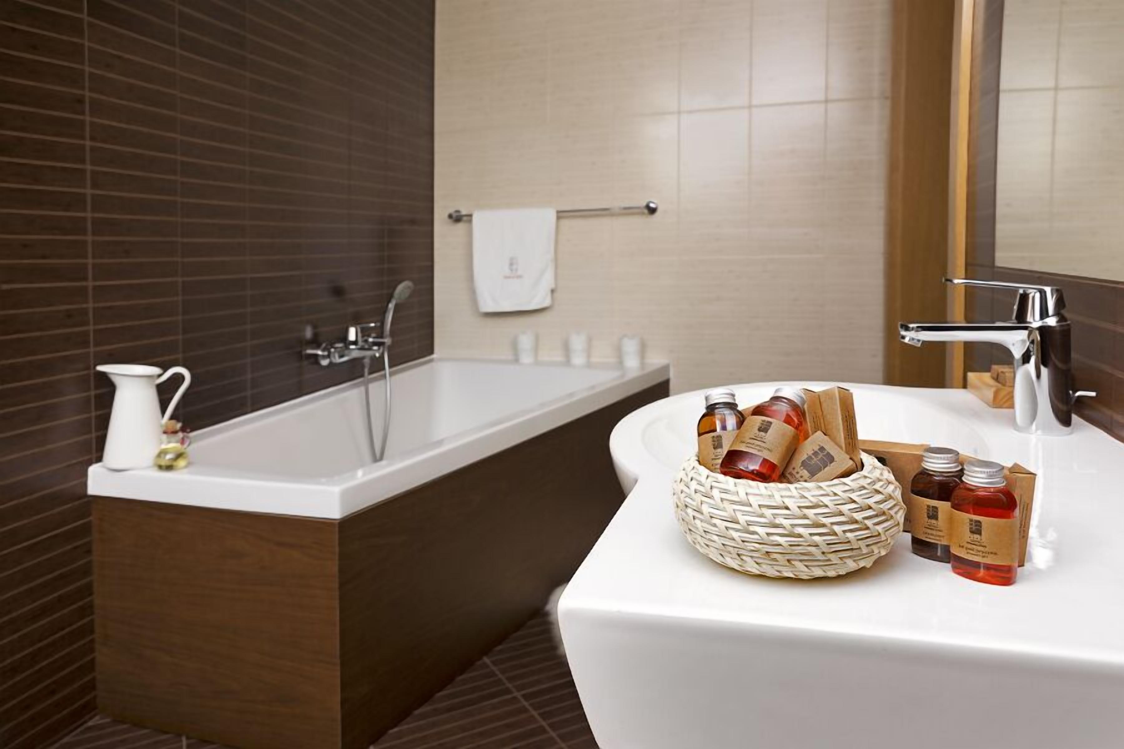 Un baño moderno con bañera, lavamanos con artículos de aseo y un perchero para toallas.