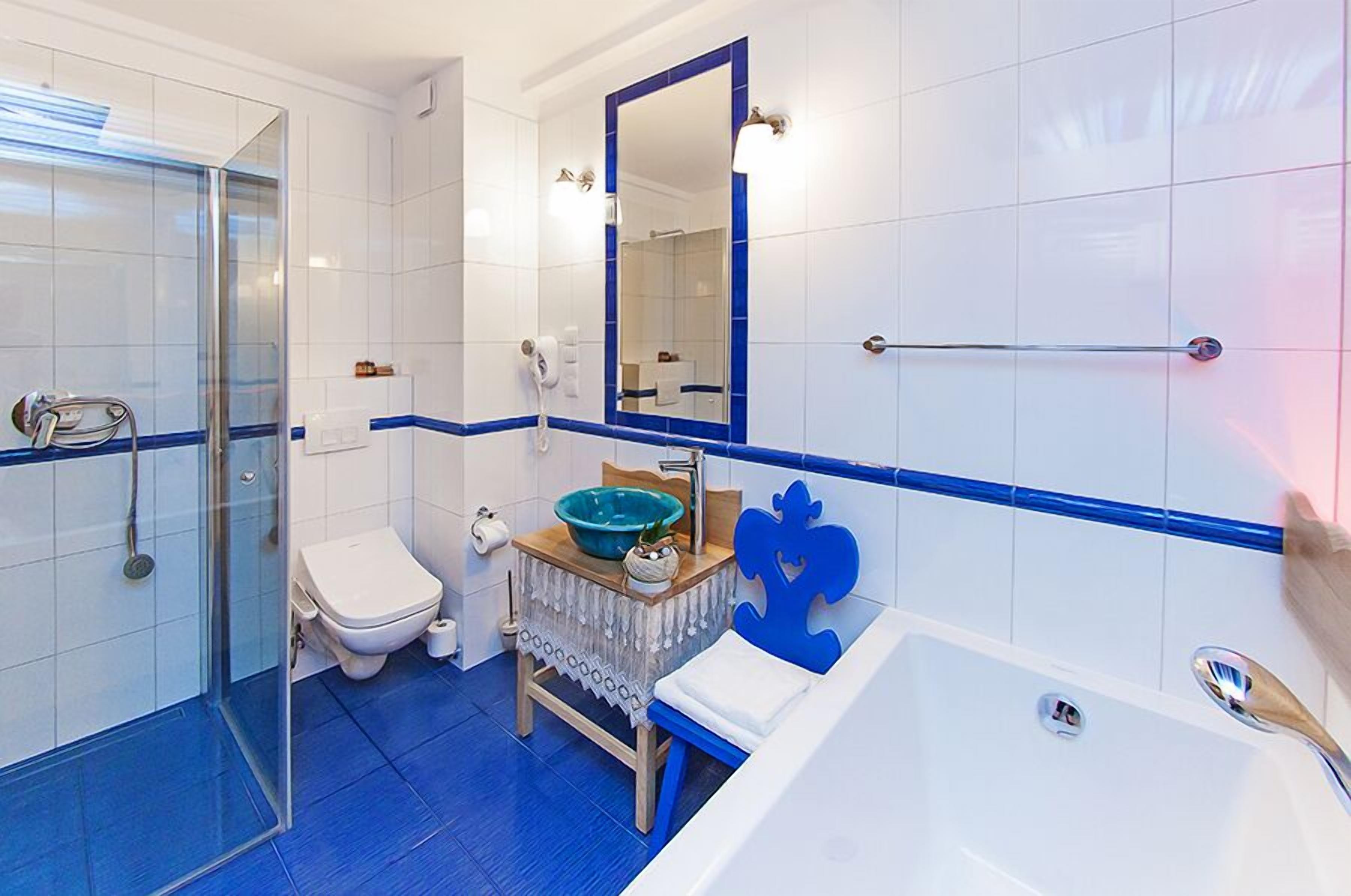 Une salle de bain avec une douche à parois de verre, des toilettes, un lavabo avec un receveur bleu et une baignoire.