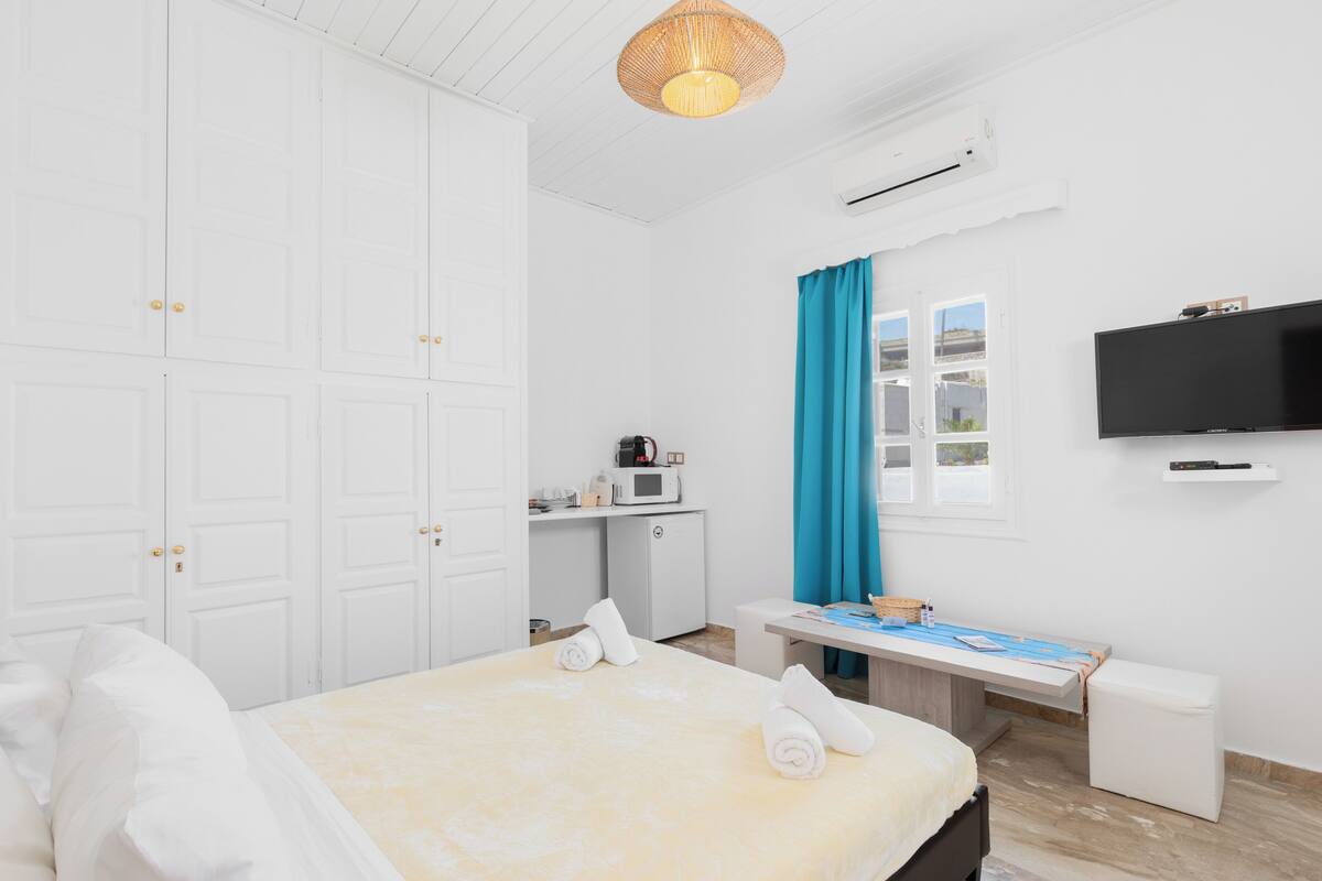 Une chambre d’hôtel équipée d’un lit, d’un bureau, d’une télévision et d’une armoire.