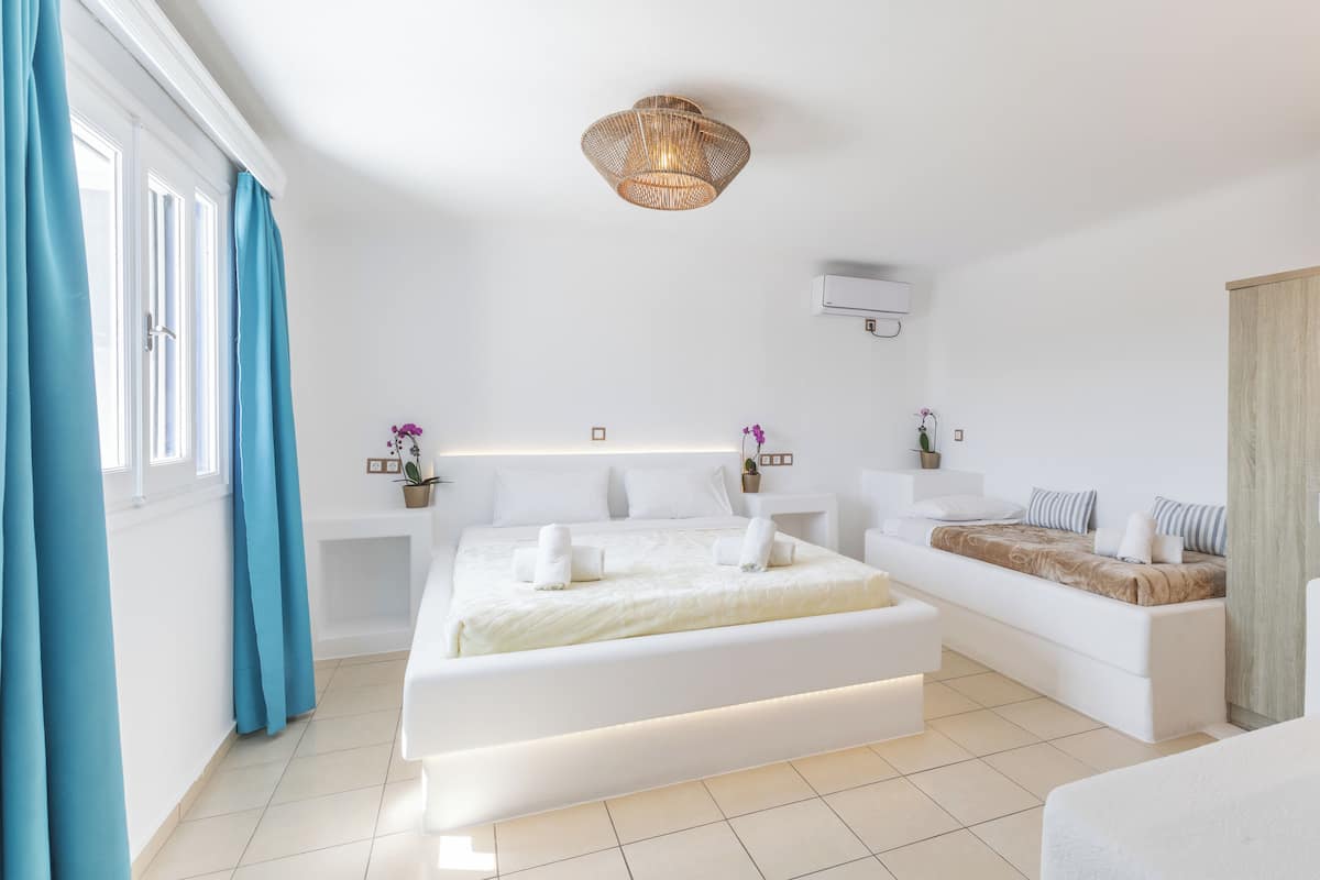 Une chambre à coucher moderne avec un grand lit, des tables de chevet, une lampe de chevet et une fenêtre avec des rideaux.