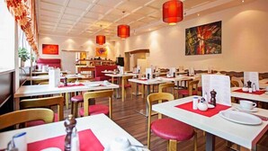 A restaurant with white tables, red cushions, and red pendant lights. - Hotel Am Bismarck (Mannheim)
