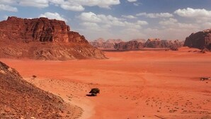 A desert landscape with rocky formations and sparse vegetation. - Wadi Rum Safari Camp (Wadi Rum)