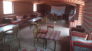 A room with striped walls and ceiling, wooden furniture, and a large window. - Wadi Rum Safari Camp (Wadi Rum)