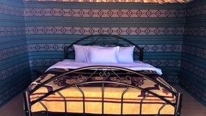 A bed with a patterned headboard and a decorative metal frame. - Wadi Rum Safari Camp (Wadi Rum)