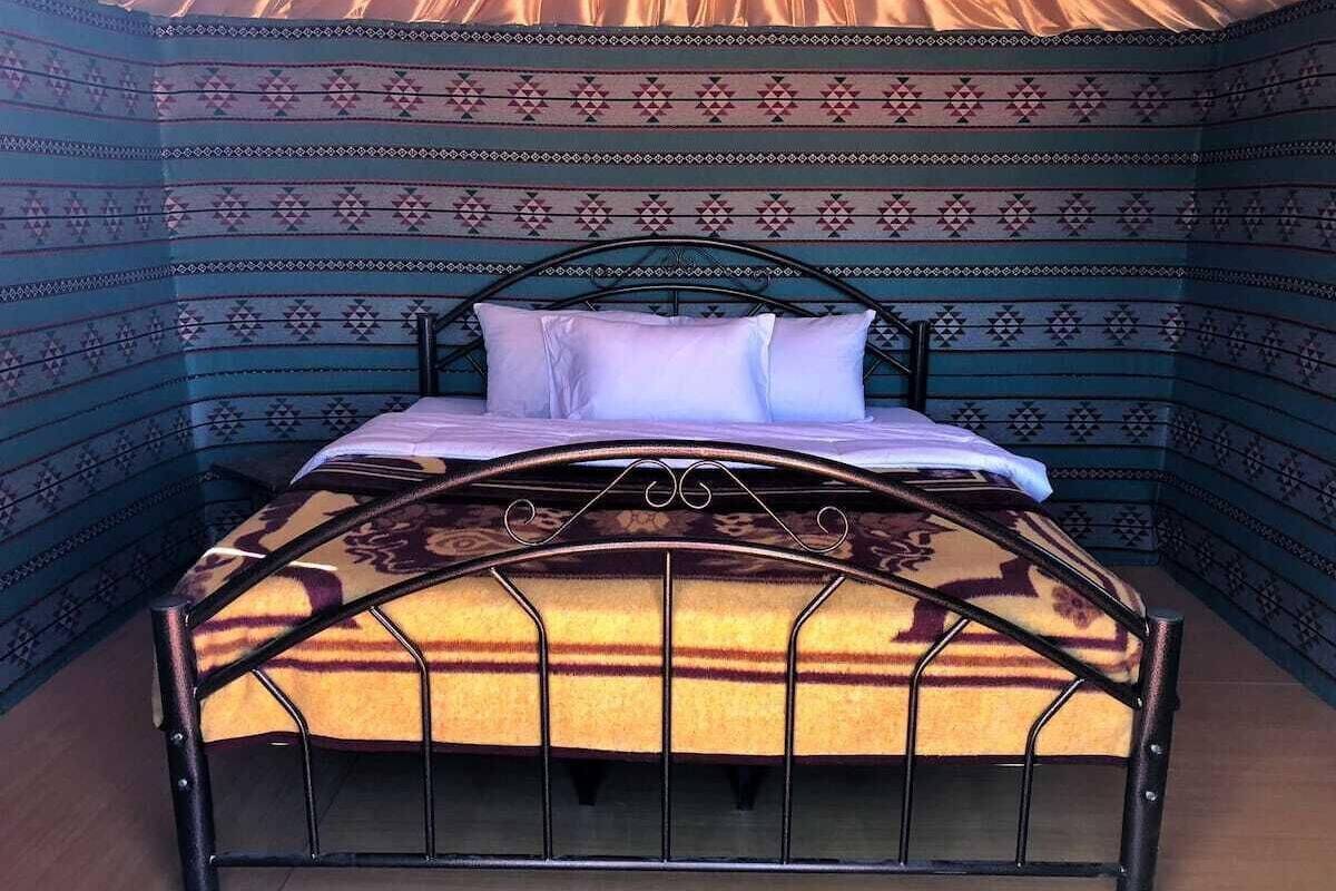A bed with a patterned headboard and a decorative metal frame.