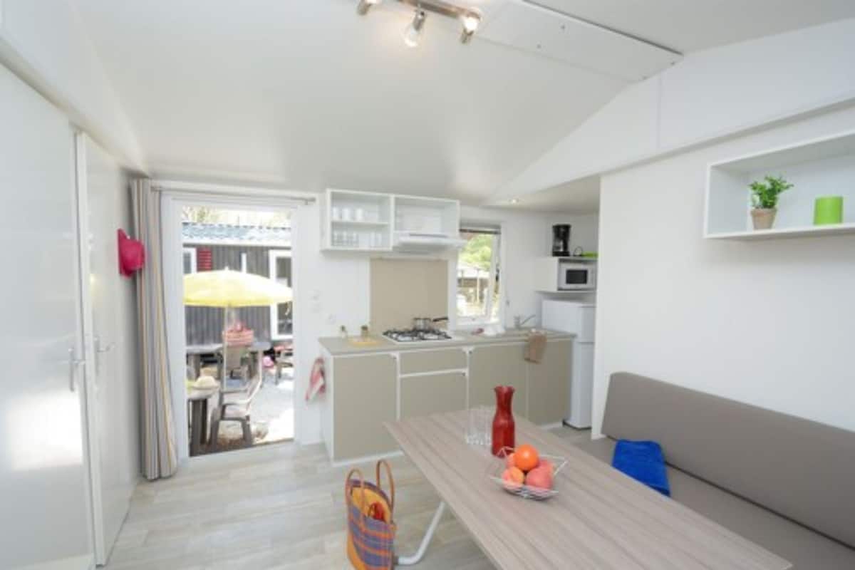Una cocina moderna con armarios blancos, una isla central y un comedor con mesa y sillas.