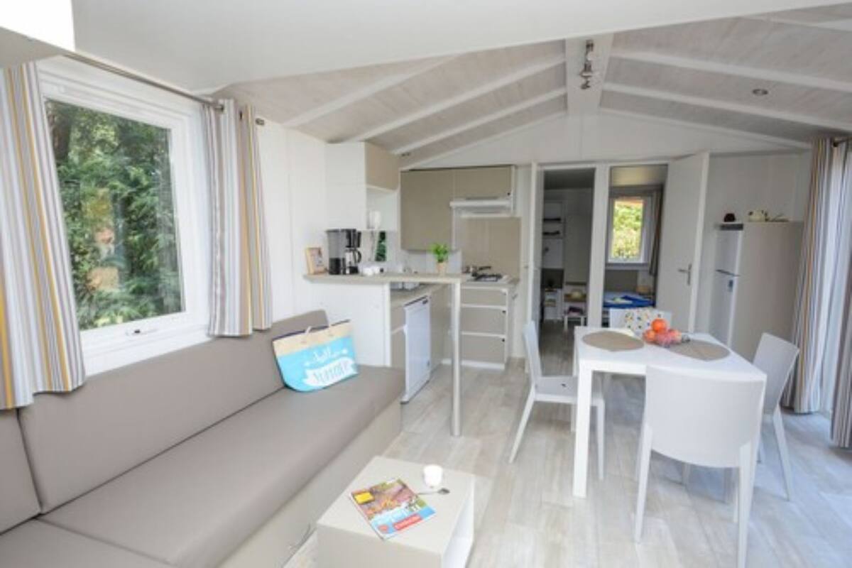 Un espacio habitable compacto con kitchenette, zona de comedor y sofá.