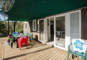 A wooden deck with a covered patio area, a table with chairs, and a glass door leading to an interior space. - Domaine De Verdagne (Gassin)