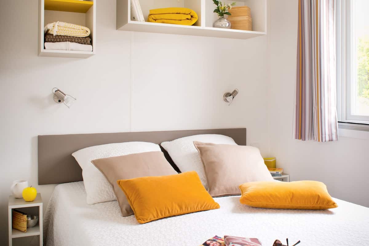 Un dormitorio ordenado con cama, mesitas de noche y estantes empotrados.