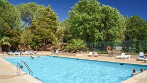A swimming pool with clear blue water, surrounded by trees and a fence. - Domaine De Verdagne (Gassin)