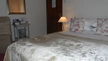 A hotel room with a bed, a nightstand, a lamp, a mirror, and a wall decoration.
