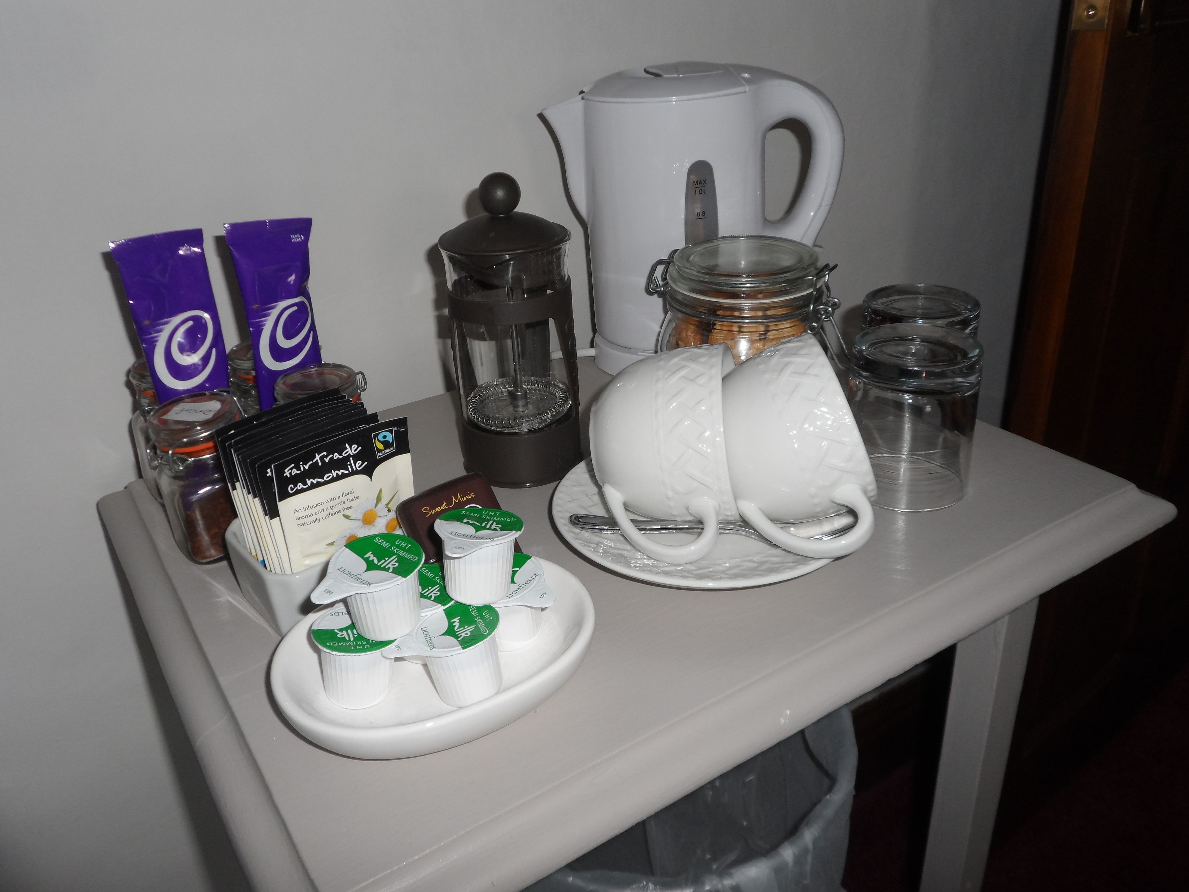 A tray with coffee-making equipment, milk, and tea bags.