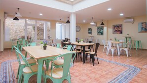 Un comedor amplio con varias mesas y sillas, ventanas grandes y un techo alto con tragaluces.