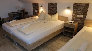 Habitación de hotel con dos camas, un escritorio y una mesita de noche.