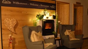 Un área de recepción acogedora con chimenea, dos sillones y un cartel de bienvenida.