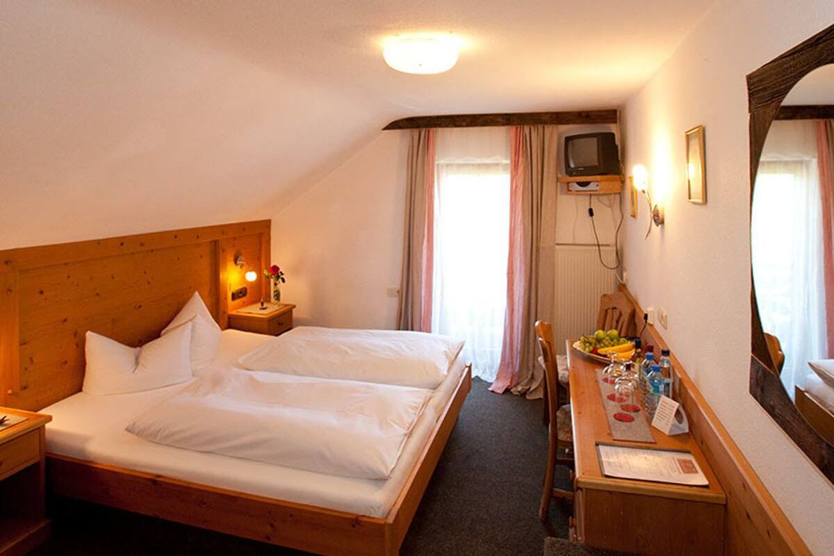 Una habitación de hotel con dos camas, un escritorio con espejo, televisión y ventana con cortinas.
