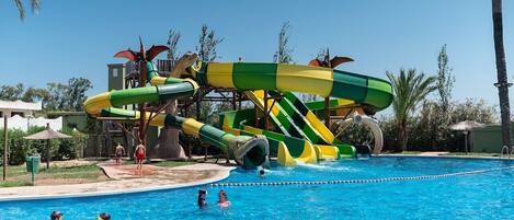 Un área de piscina con un tobogán grande y una piscina de color azul cristalino.