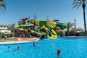 Un espace piscine doté d’un grand toboggan et d’une piscine à l’eau cristalline.