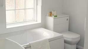 A modern bathroom with a white bathtub, toilet, and sink. - Park Hill Hotel (Lowestoft)