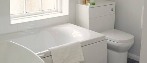 A modern bathroom with a white bathtub, toilet, and sink.