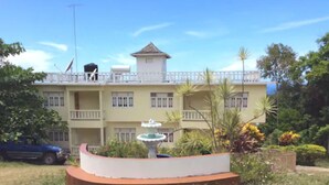 A multi-story building with a balcony, a fountain, and lush greenery. - Symphony Resort (Discovery Bay)